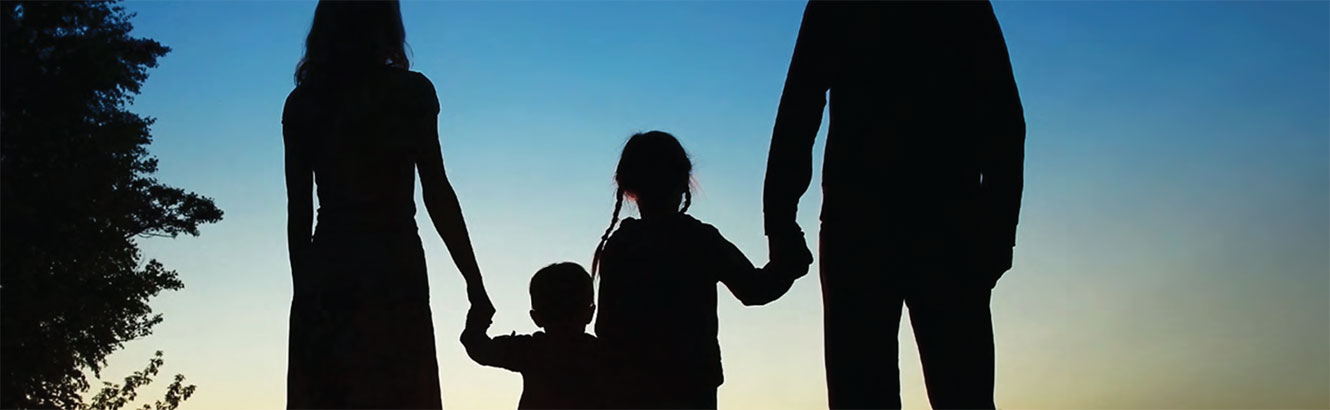 Silohuette of a family holding hands at sunset.